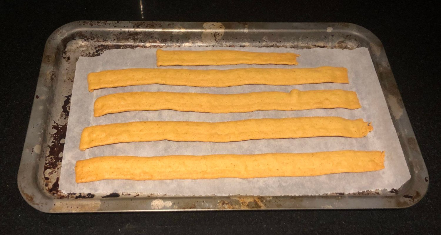 Chickpea snack ribbons laid out on a baking sheet before baking