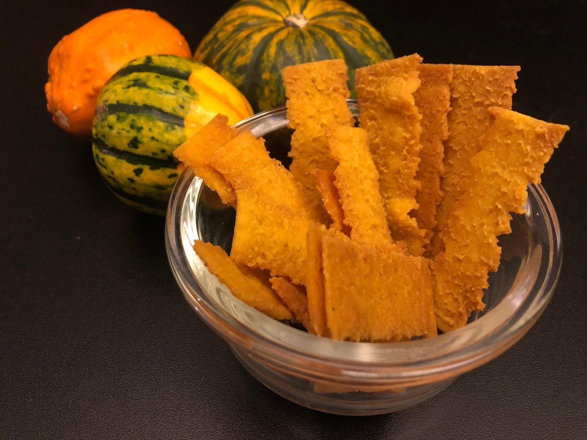 A package of Pumpkin Paprika rice chips beside decorative pumpkins